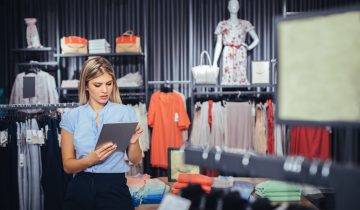 Photo of a young woman using digital tablet in the store.