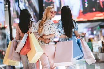 Three attractive young girls are doing shopping with shopping bags in modern mall.