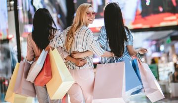 Three attractive young girls are doing shopping with shopping bags in modern mall.